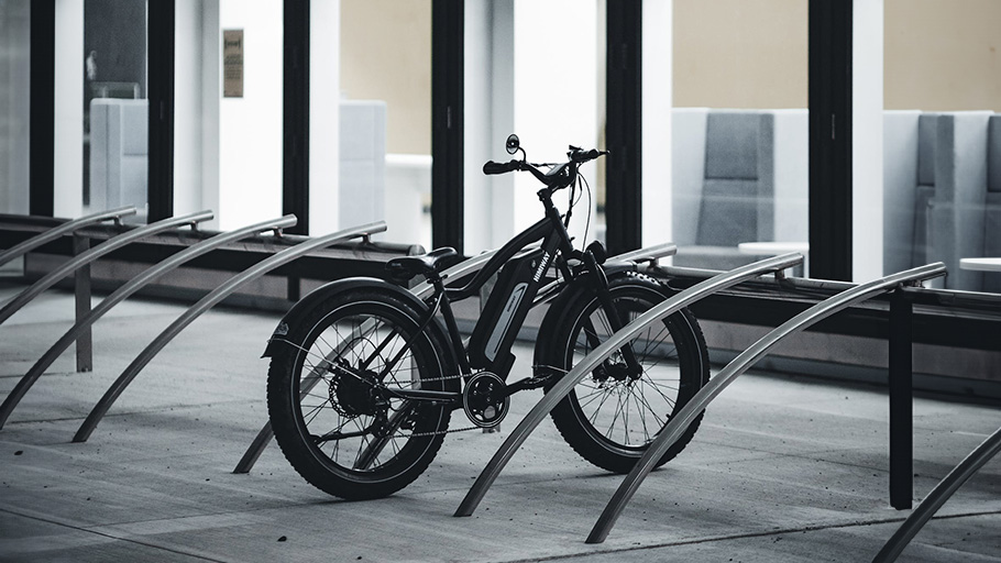 A bike secured at a minimalist stainless-steel rack, offering functionality and style in urban settings.
