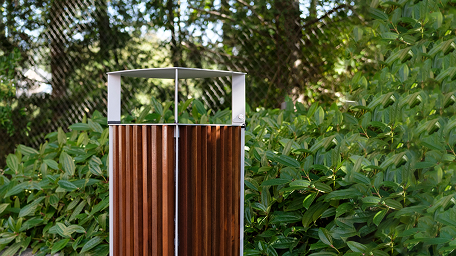 wood and metal waste receptacle in front of bushes