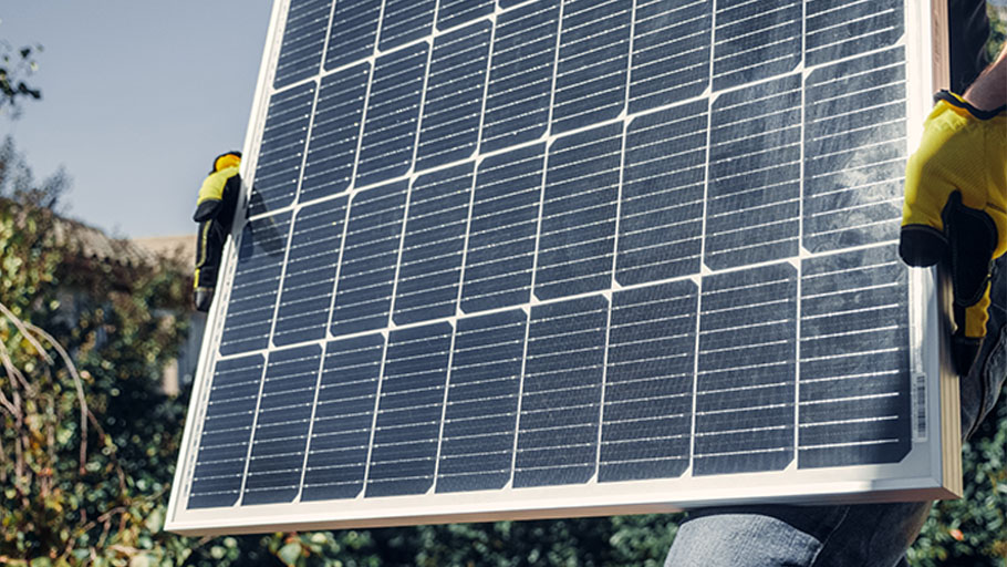 A worker carrying a large solar panel.