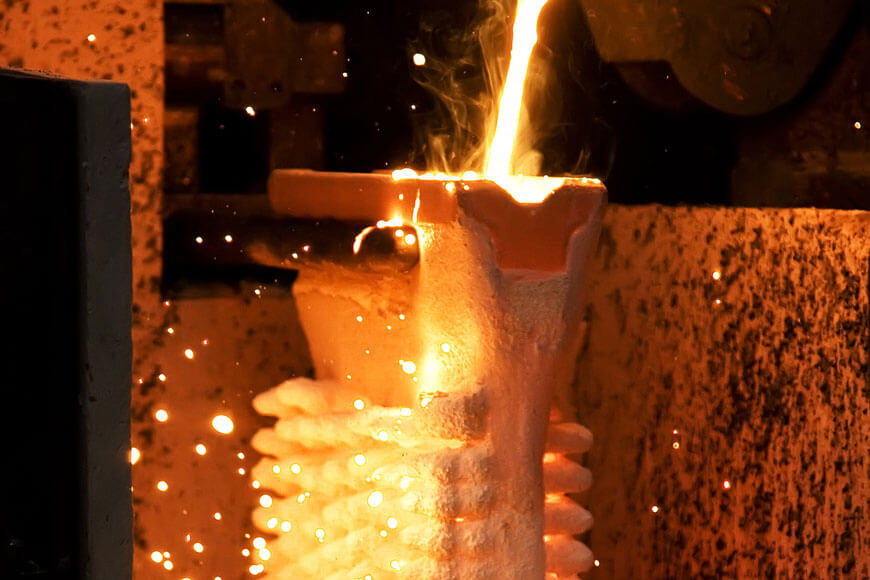 Molten metal poured from ladle into mold during lost wax casting
