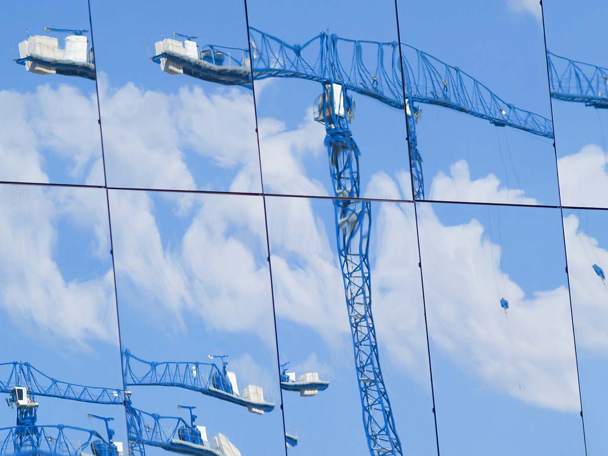 Construction cranes reflected in glass