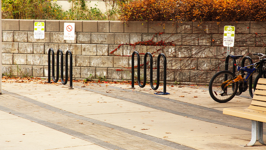 An image of multiple bike racks in front of a stone retaining wall
