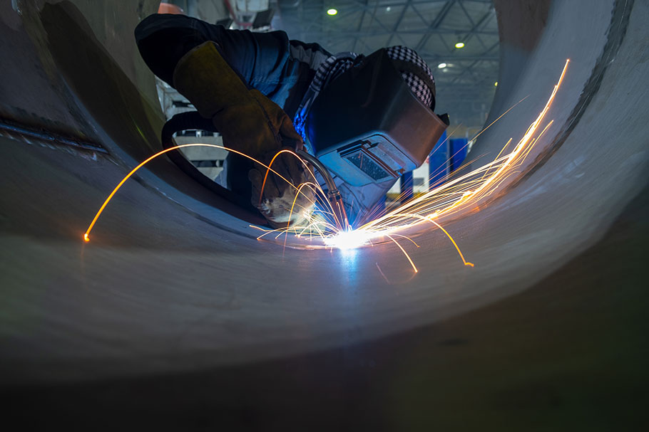 Sparks fly as a welder works on stainless steel piping