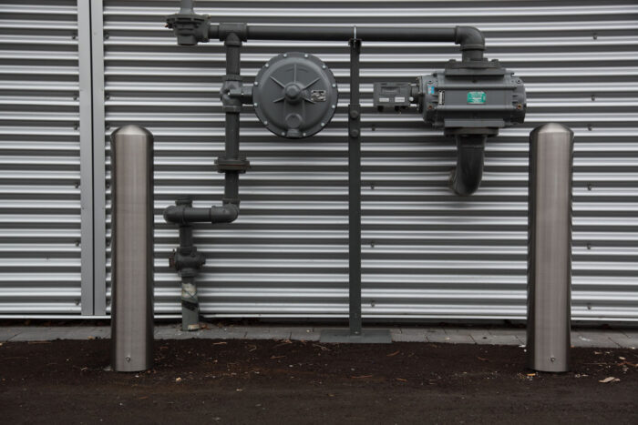 R-7301 stainless steel bollard protecting utility meter on wall