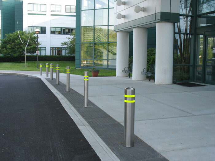 R-7305 stainless steel bollard covers with yellow reflective strips in front of glass building
