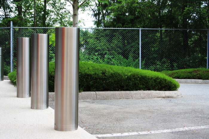 Three R-7311 stainless steel bollard covers in parking lot