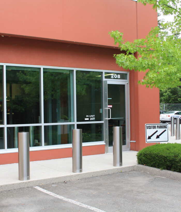 Three R-7311 stainless steel bollard covers at front of parking stalls