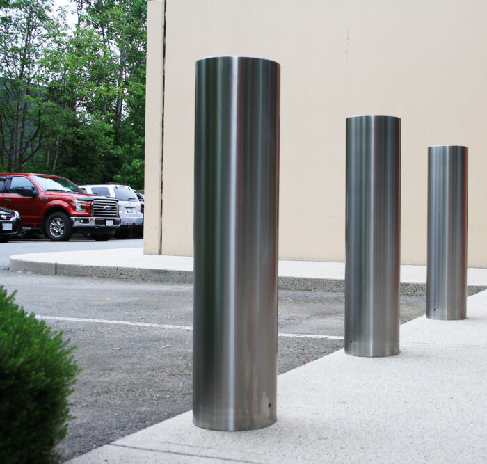 Three R-7311 stainless steel bollard covers in parking lot