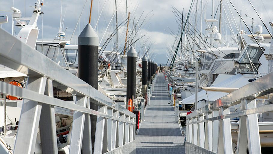 A stainless steel ramp leading down to a marina on a sunny day