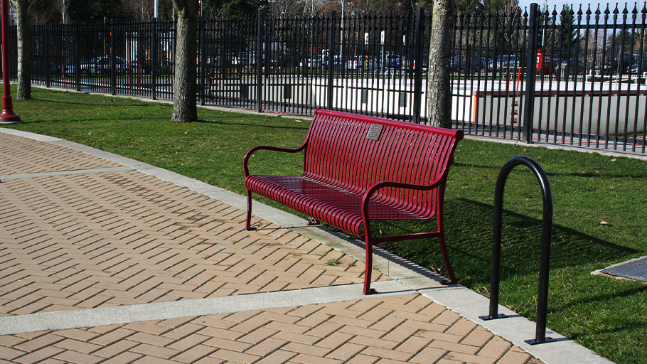 A u-style bike rack installed next to a park bench