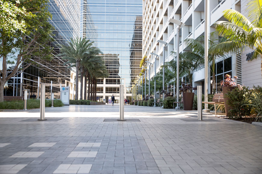 Three silver bollards provide physical access control to a business plaza