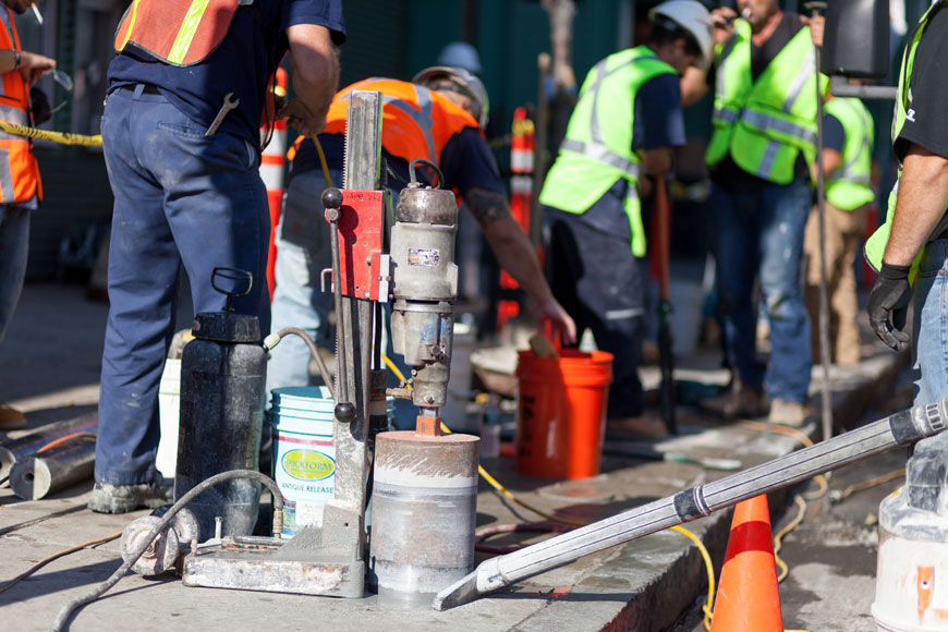 An auger bores a round hole out of the sidewalk that runs along Lansdowne Street, outside Fenway Park.