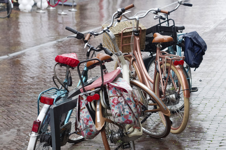 Bikes with panniers are parked in the street on a rainy day.