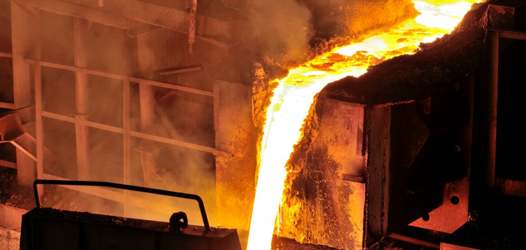 At a foundry, hot molten steel flows from a blast furnace before being cast into ingots