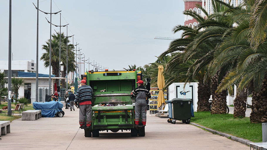 A garbage truck drives down a boardwalk