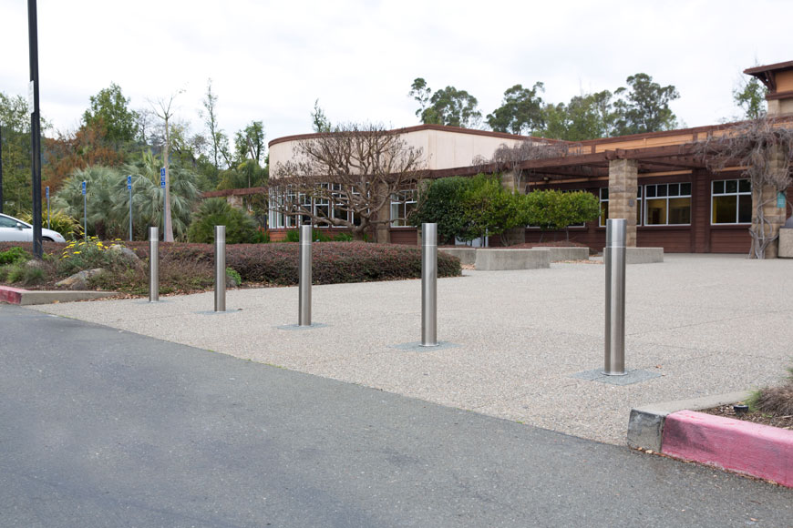 Stainless steel retractable bollards protect the front of a low brown and tan building