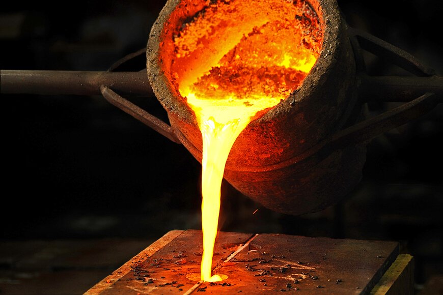 Pouring molten iron into a sand casting mold