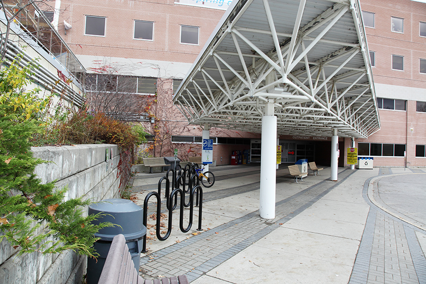 The reception bay of a hospital features bike racks, trash and recycling cans, and benches