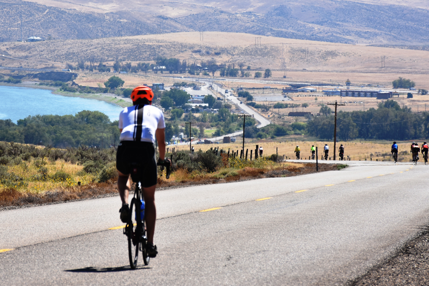 Cyclists ride down a long slope through a scenic vista in Oregon.