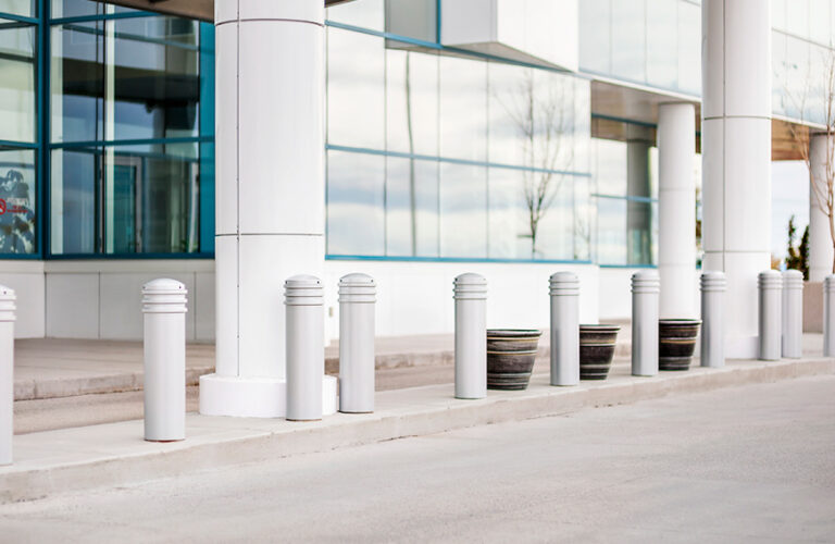 White bollards blend in with a white and glass building