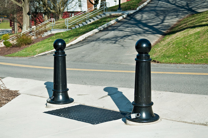 Two pawn-shaped R-7589 decorative cast iron bollards sit locked to removable economy mounts