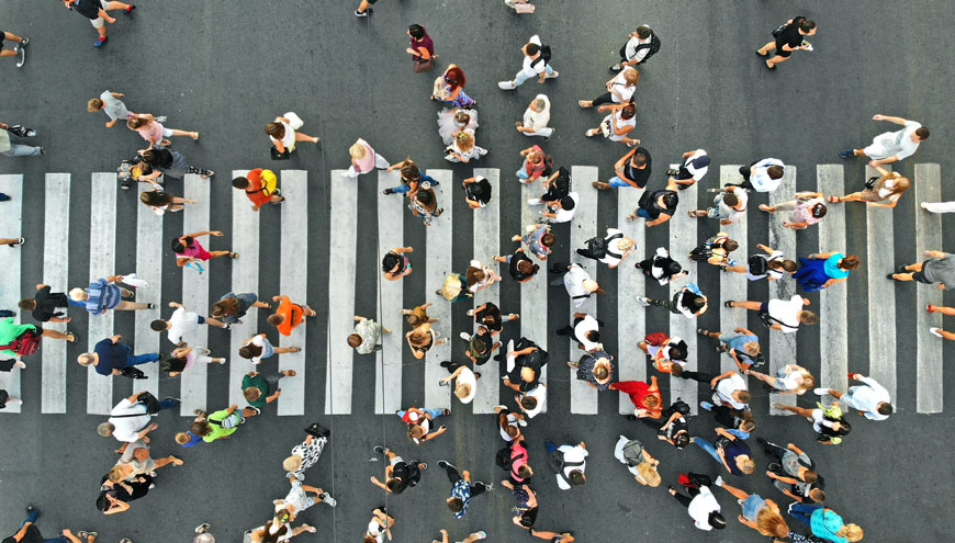 A top down shot of many pedestrians using a zebra crossing