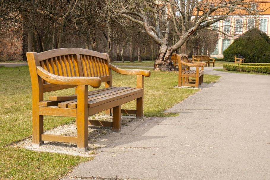 An empty wooden bench sitting alongside a pathway