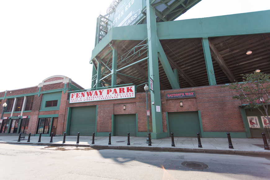 A line of shiny black decorative bollards protects the red brick façade of Fenway Park