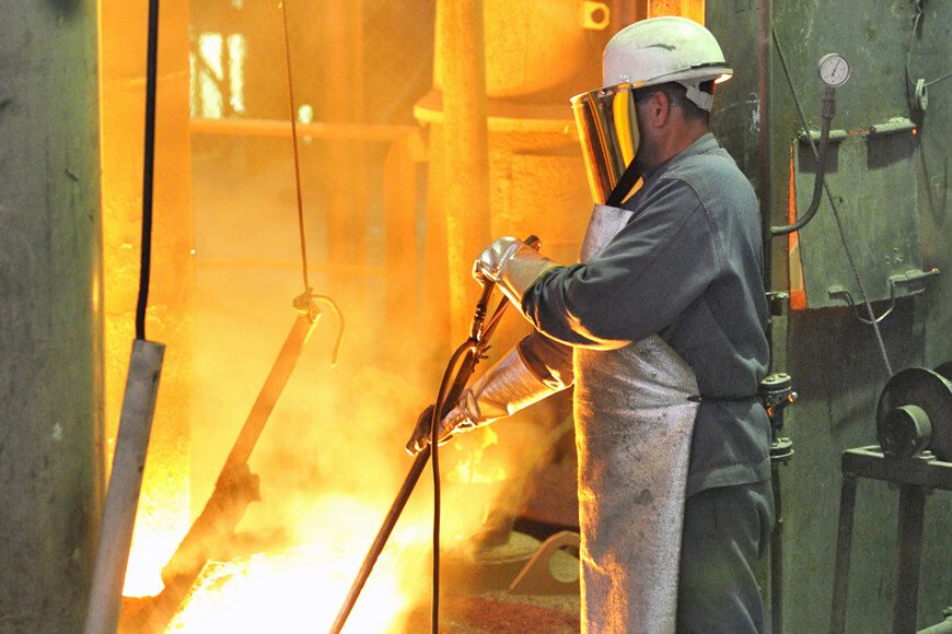 A worker testing metal temperature wearing foundry safety clothing