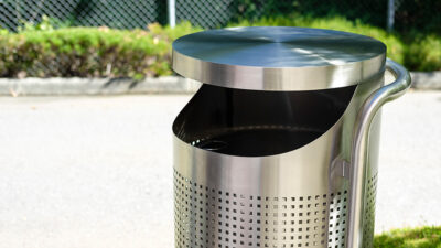 A stainless steel garbage bin in a park