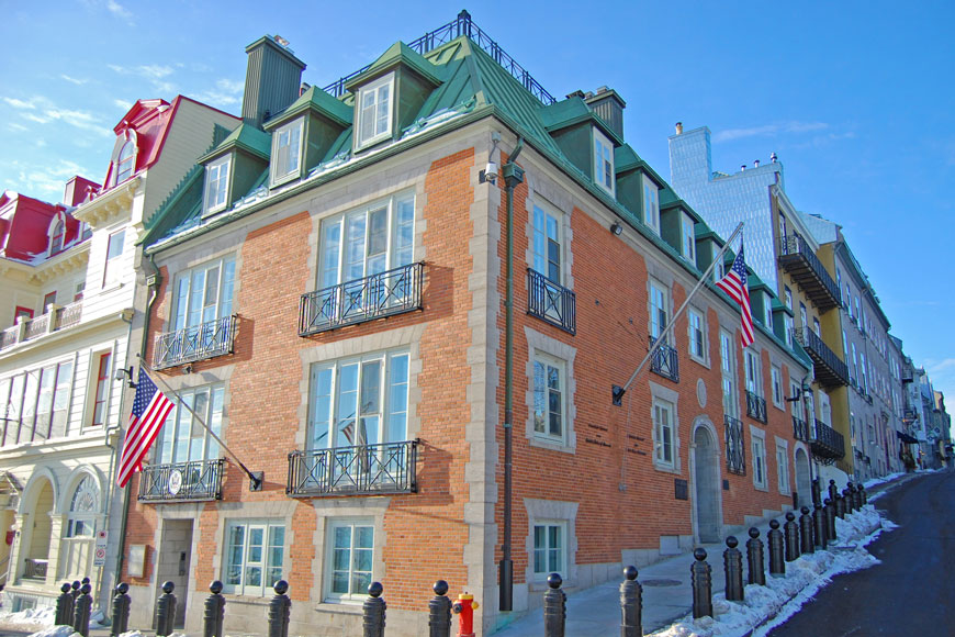 A red brick building in a Reserved French Chateau style is surrounded by black cannon bollards