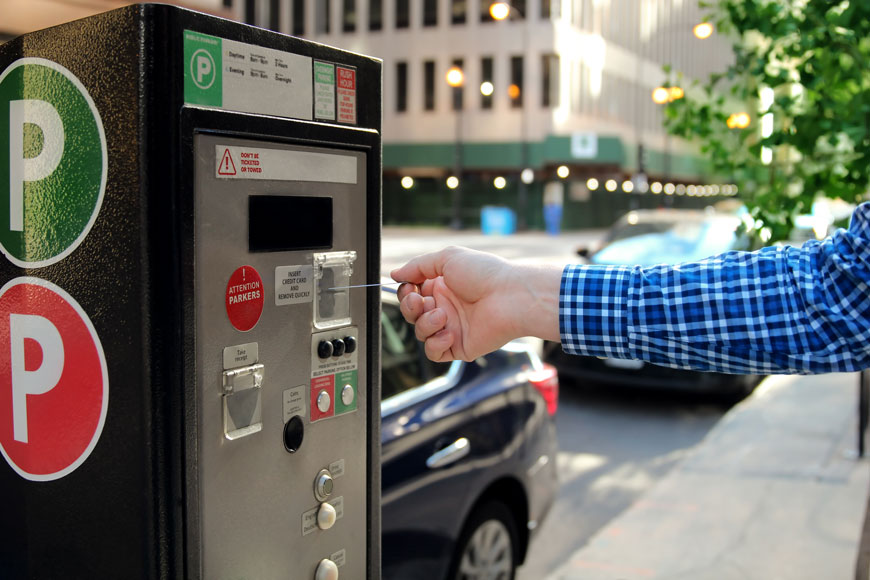 A man puts his credit card into a machine to pay for hospital parking