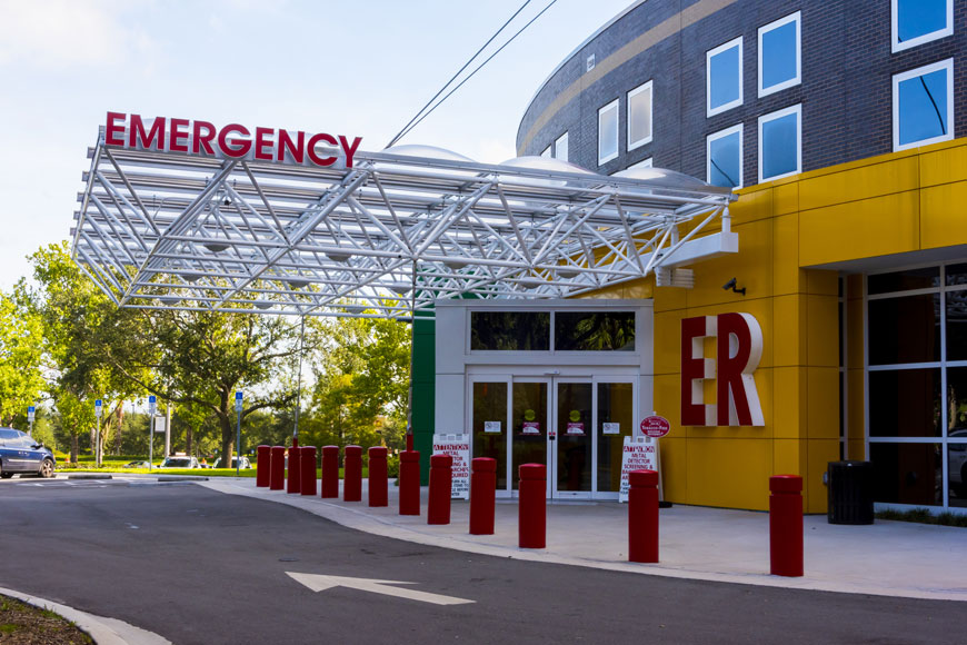 Bright red bollards protect the entrance to a hospital emergency room