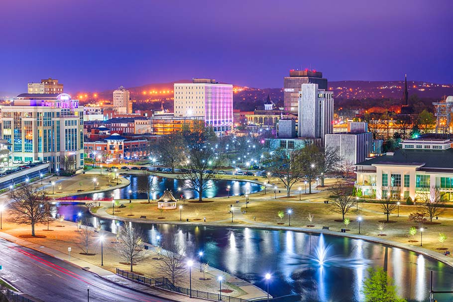 An image of the skyline of Huntsville, AL at night with lights shining from buildings and parks