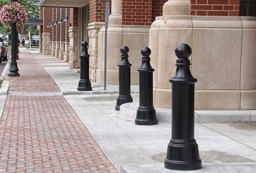 Large black cannon bollards protect the vehicle entrance of a red brick building