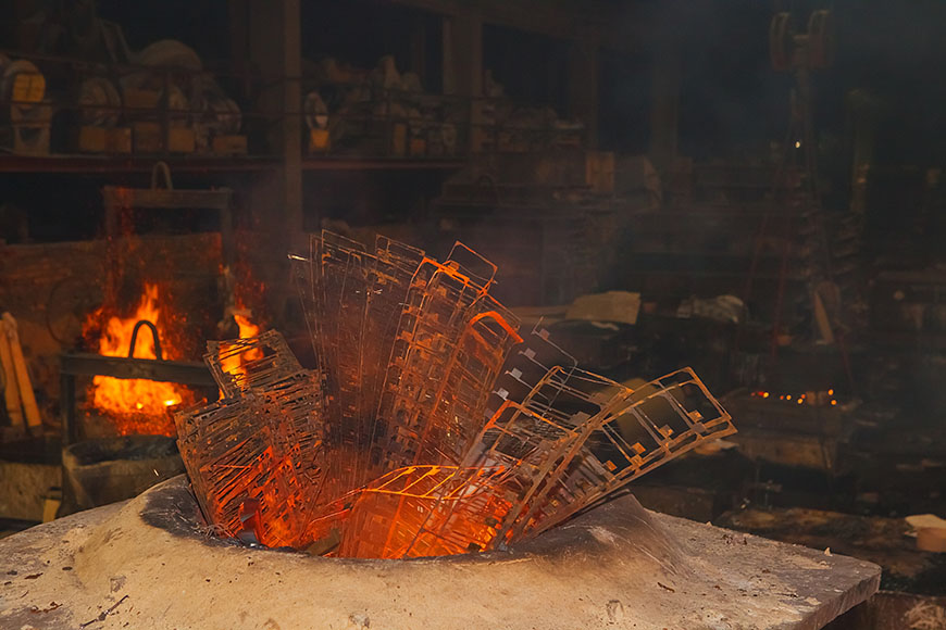 Thin metal scraps protrude from a dirty induction metal furnace and are red with rust and heat