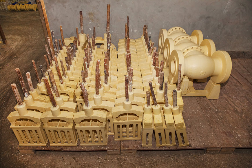 A series of yellow wax objects wait to be covered in molding ceramic