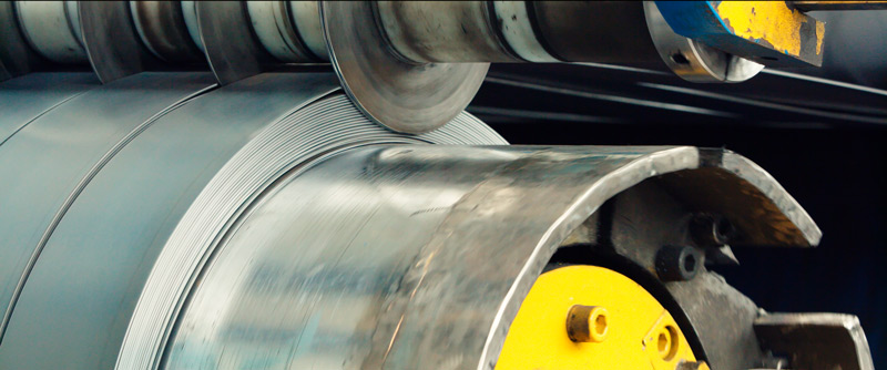 Una gran máquina corta una lámina de acero en tiras y las hace girar en una bobina