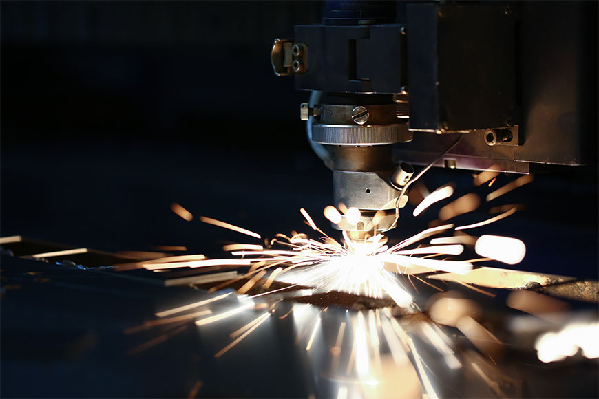 Sparks fly out as steel is being cut and fabricated by a laser cutting machine