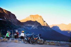 Cyclists take a break against a mountain backdrop