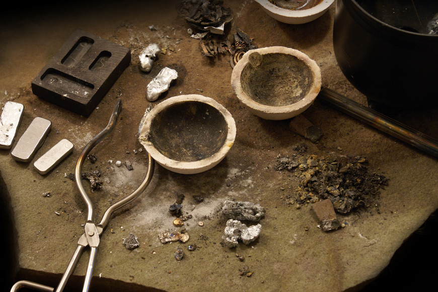 Un métallurgiste non ferreux laisse des lingots d'argent et des pépites d'or à côté des creusets et des moules 