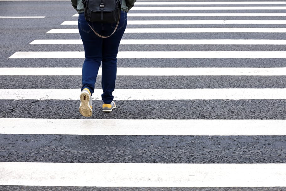 A pedestrian crosses the street at a crosswalk