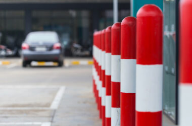 Brightly painted red and white striped bollards create a barrier in a parking lot