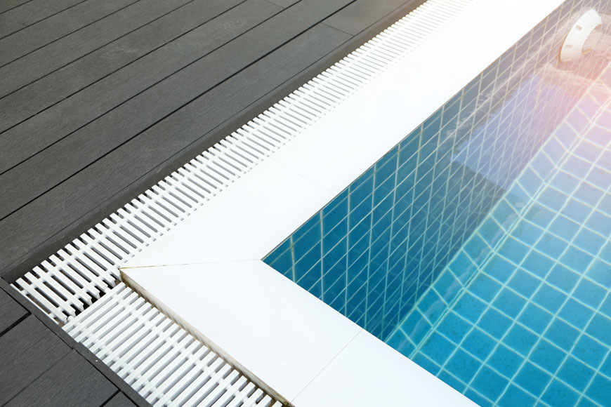 White bar pool grates contrast to deep blue tile around a pool