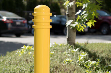 Yellow safety bollard with annular rings in parking lot