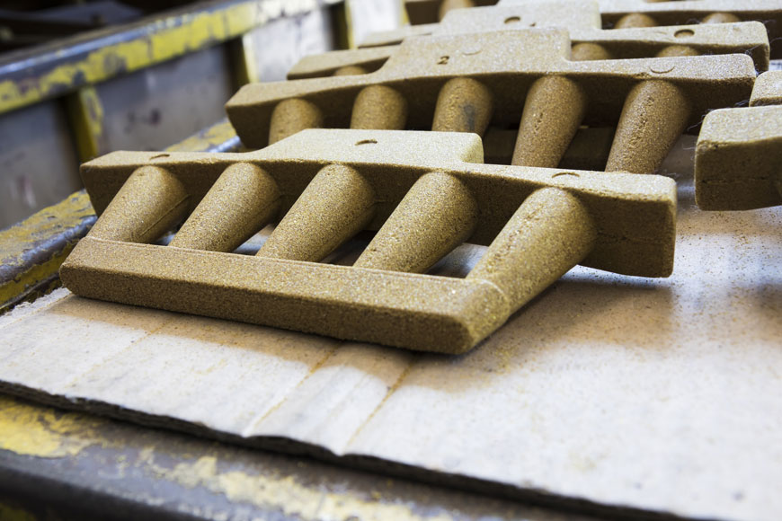 Resin-coated sand cores with five columns on a formed handle and base are ready for iron casting.