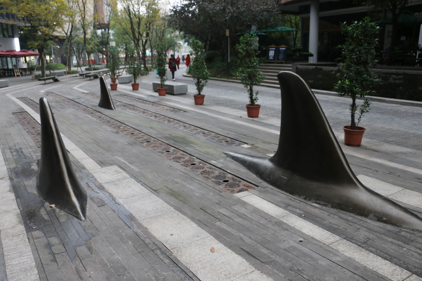 Bollards shaped like fins stick out of the ground along a sidewalk
