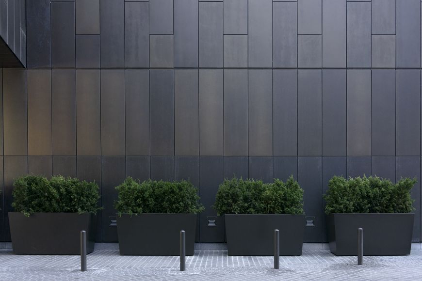 Grey monotone bollards, planters, and wall make a modern looking security perimeter