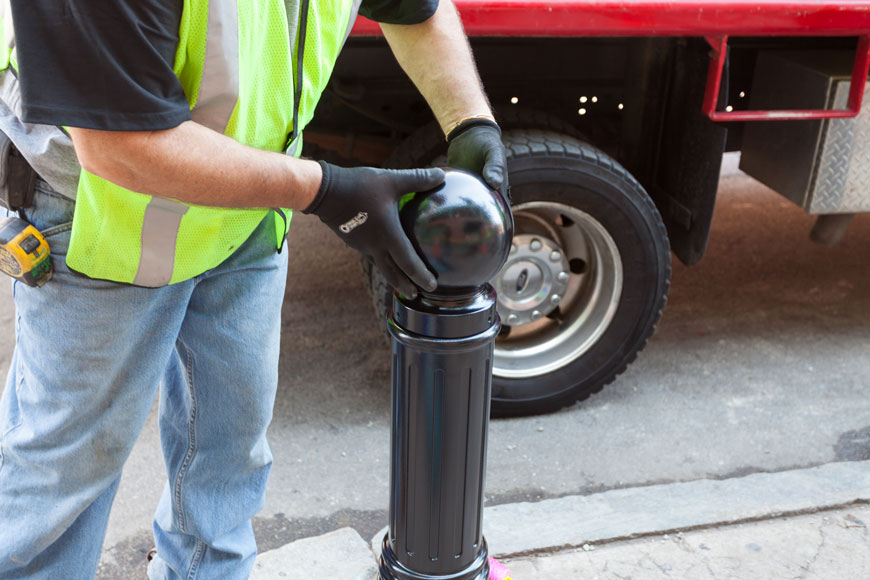 A cap is installed on the body of a bollard outside Fenway Park in Boston.