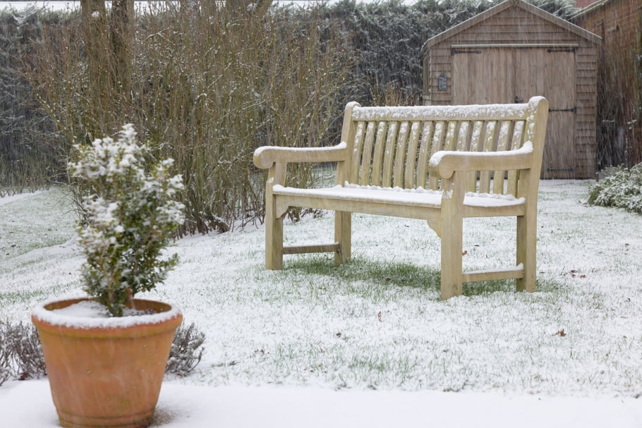A teak bench covered in snow